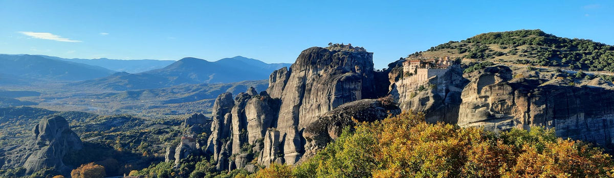 Cliffside monasteries perched atop the sandstone pillars of Meteora, Greece, overlooking an autumn valley.